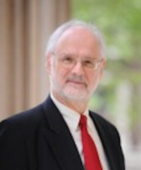 Karl Sauvant is wearing a dark suit, white shirt and red tie